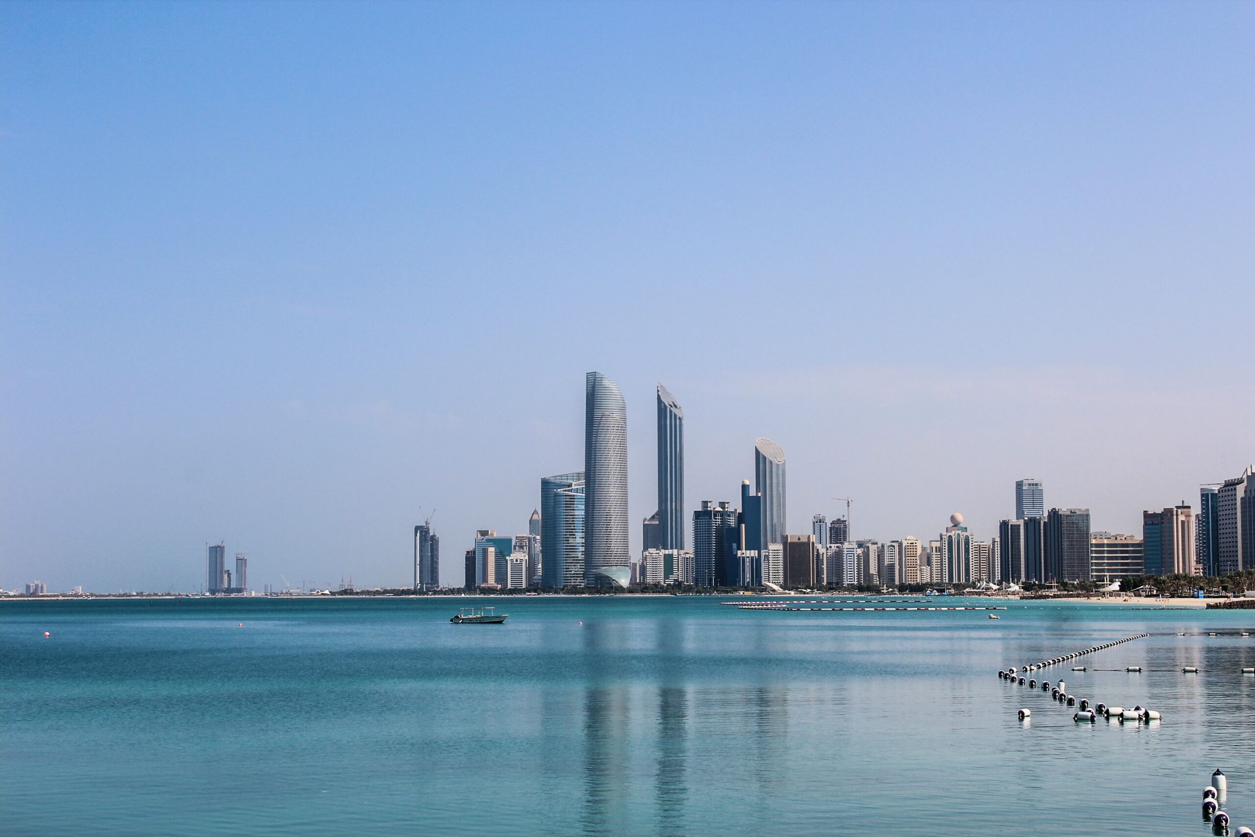 Abu Dhabi skyline and waterfront across turquoise water.