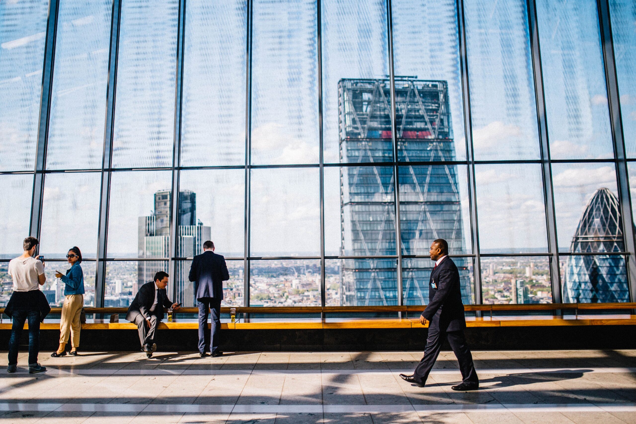 People overlooking the City of London skyline through large windows.